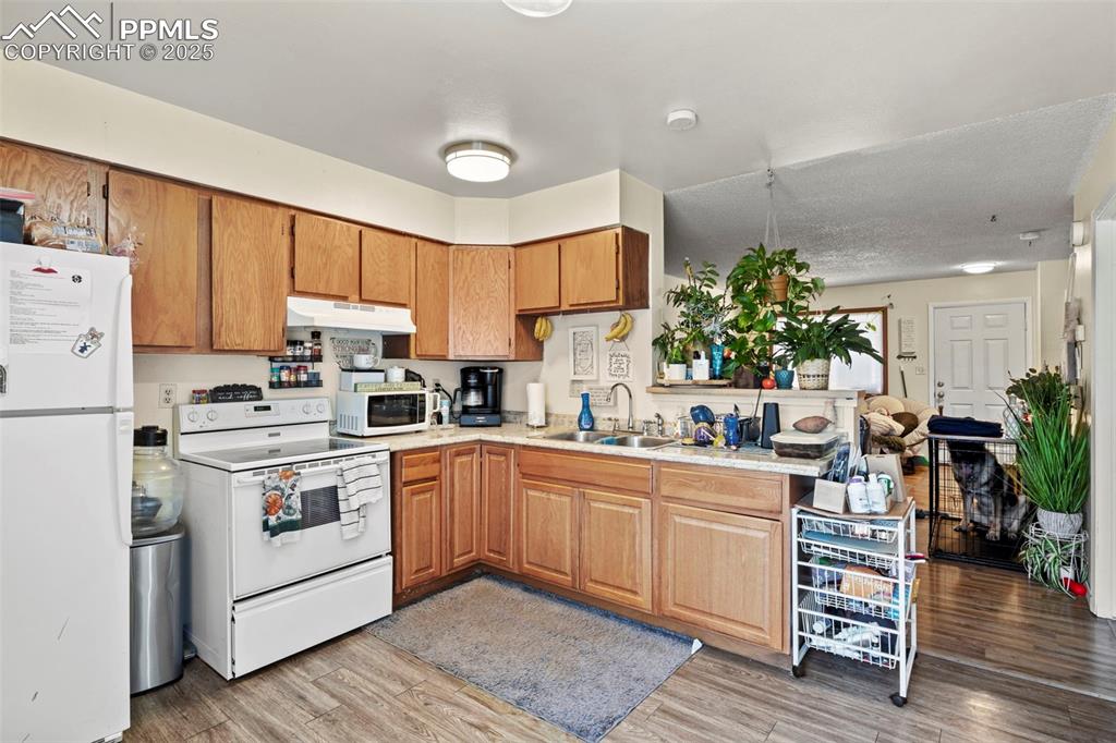 Image 14 of 31: Kitchen featuring white appliances, brown cabinets, light wood-type floorin
