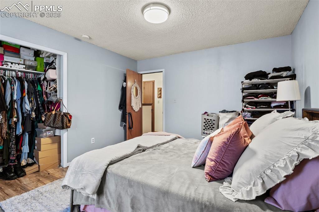 Image 20 of 31: Bedroom featuring a textured ceiling, a closet, and wood finished floors