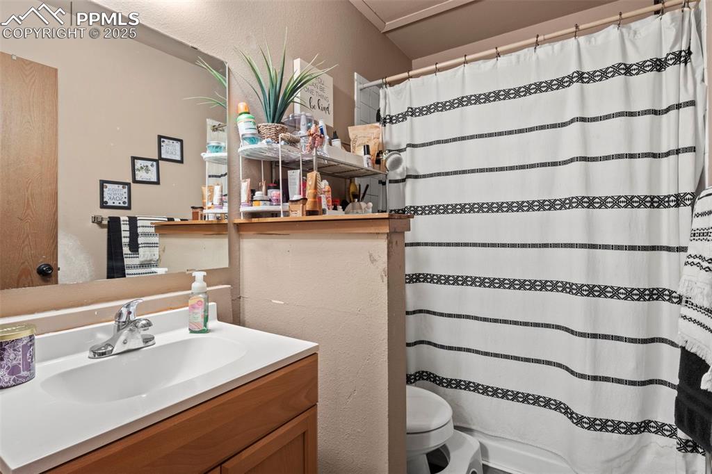 Image 21 of 31: Full bathroom featuring vanity, curtained shower, and a textured wall