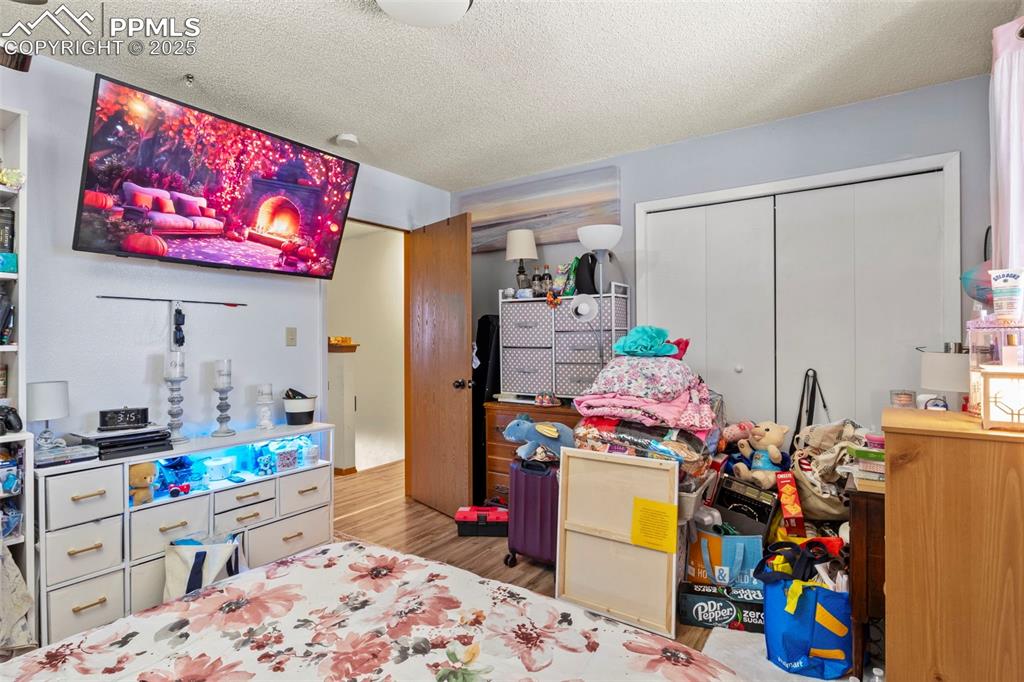Image 23 of 31: Bedroom featuring a textured ceiling, a closet, and light wood-style floors