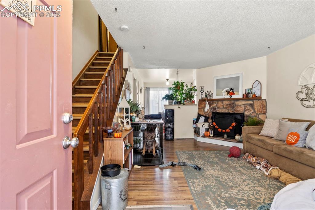 Image 6 of 31: Living room featuring wood finished floors, a textured ceiling, a stone fir