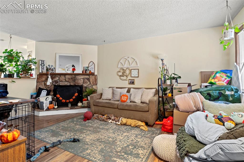 Image 8 of 31: Living area featuring wood finished floors, a textured ceiling, and a firep