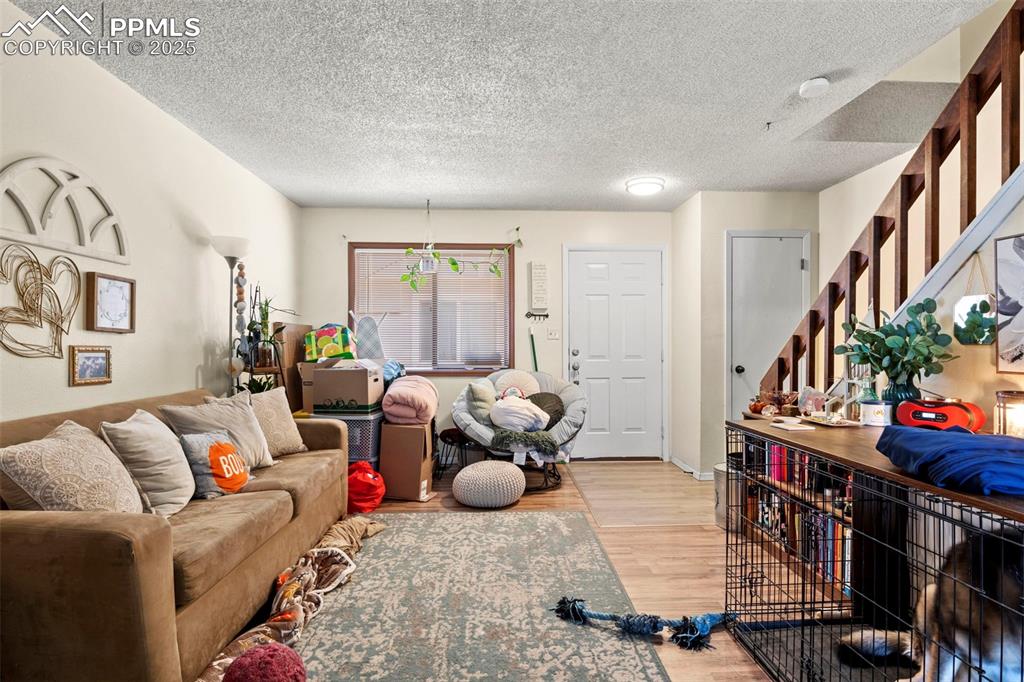 Image 9 of 31: Living room with stairway, a textured ceiling, and light wood-type flooring