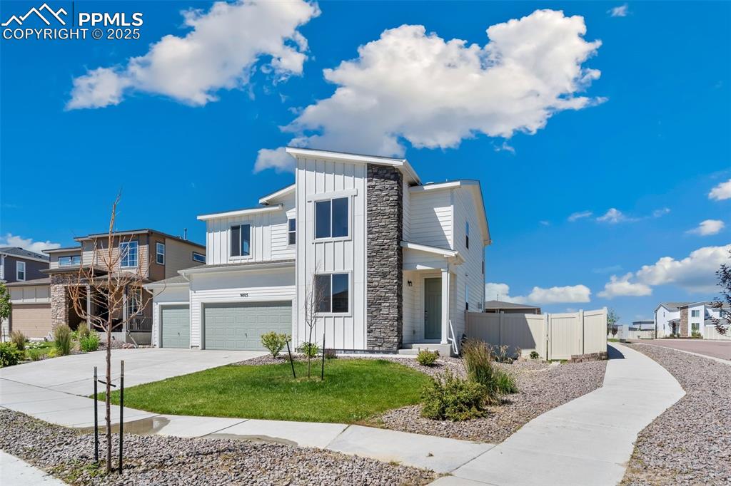Caption: Contemporary house with board and batten siding, a garage, concrete driveway, stone siding, and a re