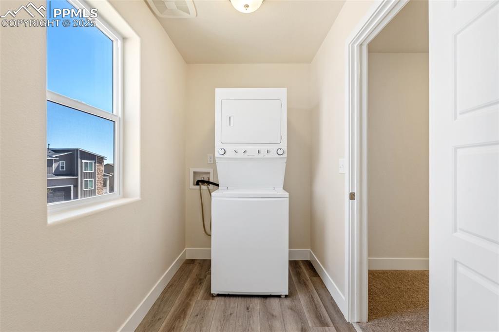Image 12 of 35: Washroom featuring stacked washing machine and dryer and wood finished floo
