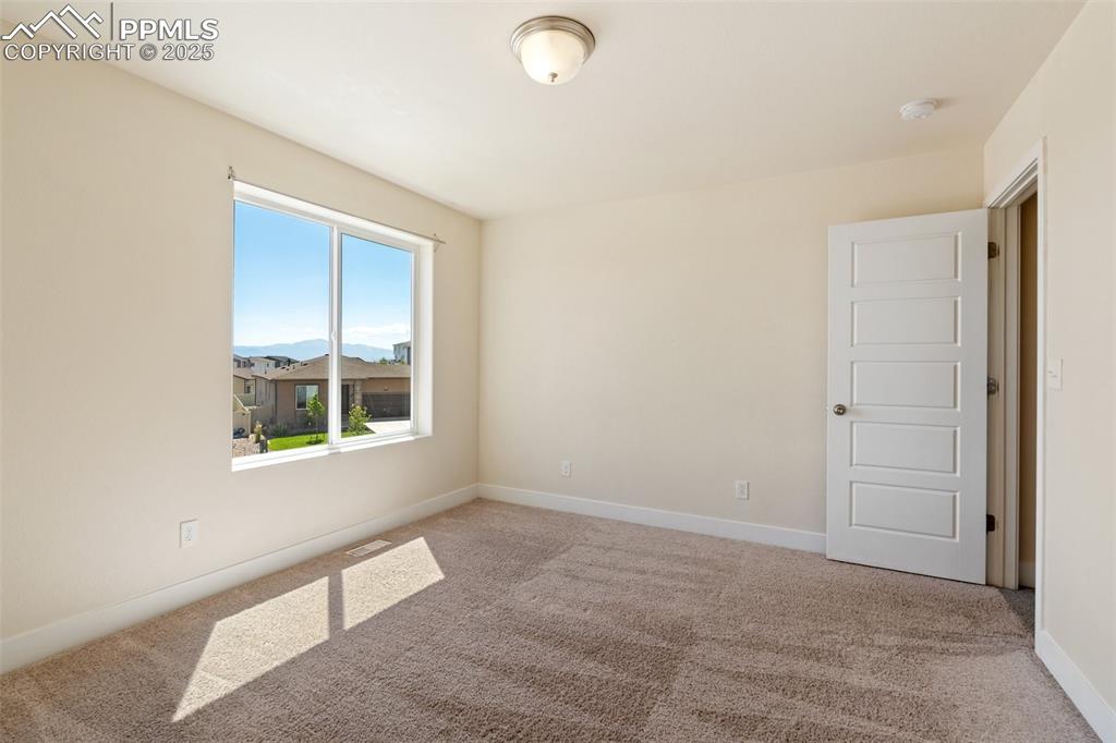 Image 14 of 35: Empty room with a smoke detector and light carpet