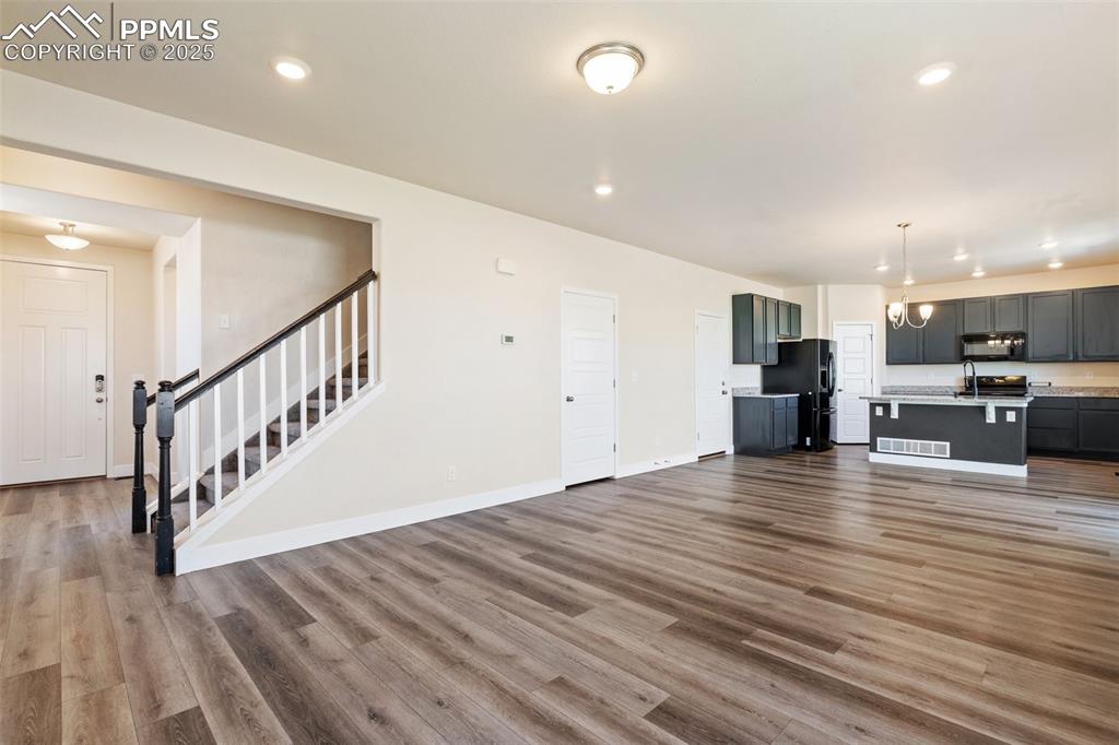 Image 4 of 35: Unfurnished living room with stairway, wood finished floors, and recessed l