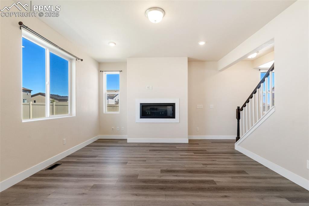 Image 6 of 35: Unfurnished living room featuring wood finished floors, a glass covered fir