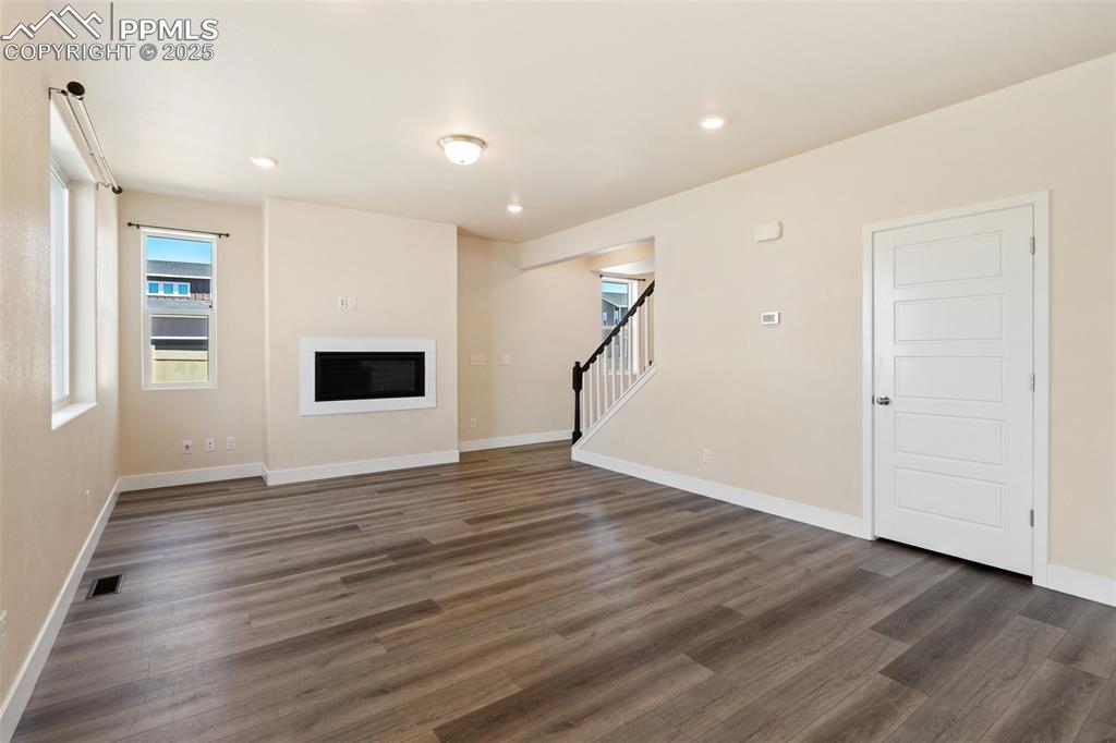 Image 7 of 35: Unfurnished living room featuring stairs, dark wood-type flooring, a glass