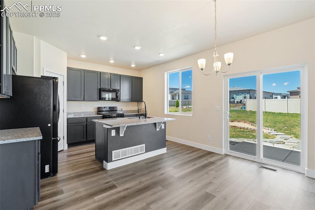 Image 8 of 35: Kitchen with black appliances, wood finished floors, a chandelier, a kitche