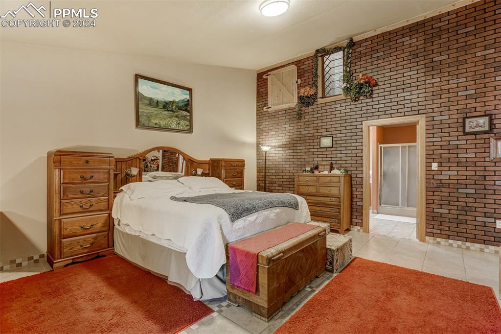 Image 28 of 48: Tiled bedroom featuring brick wall