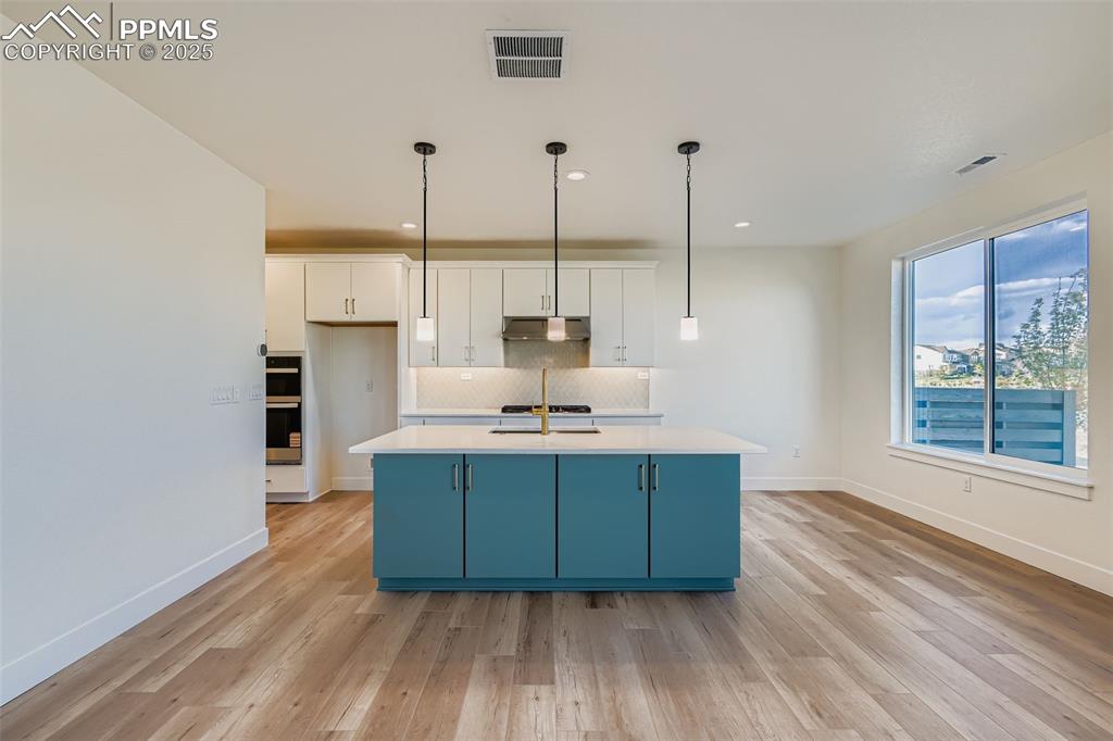 Image 10 of 28: Kitchen featuring white cabinetry, decorative backsplash, decorative light 
