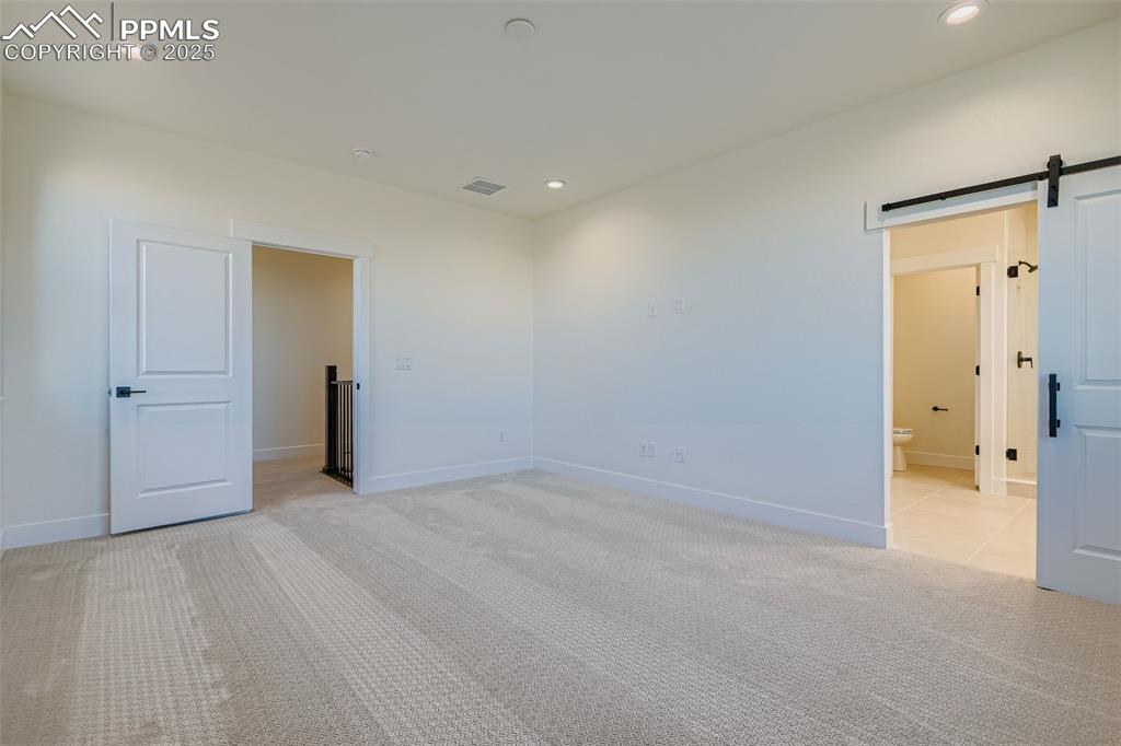 Image 14 of 28: Unfurnished room featuring a barn door, light colored carpet, and recessed 
