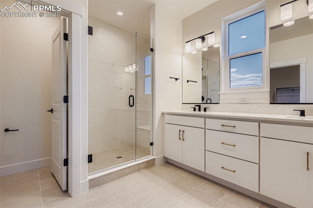 Image 15 of 28: Full bathroom featuring a stall shower, double vanity, light tile patterned