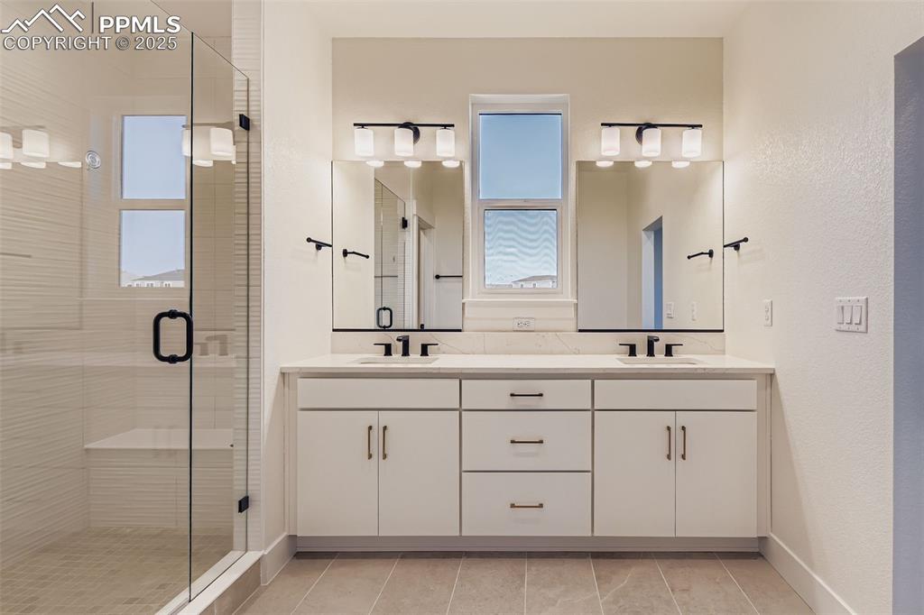 Image 16 of 28: Bathroom featuring a stall shower, double vanity, and a textured wall