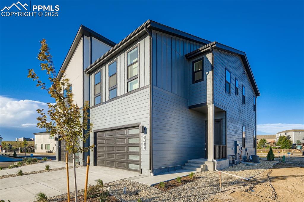 Image 2 of 28: View of property exterior featuring a garage, driveway, and board and batte