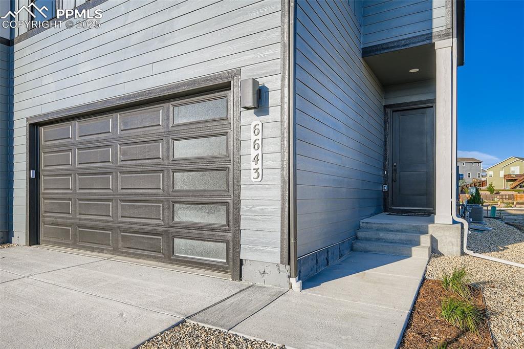 Image 3 of 28: Doorway to property featuring a garage