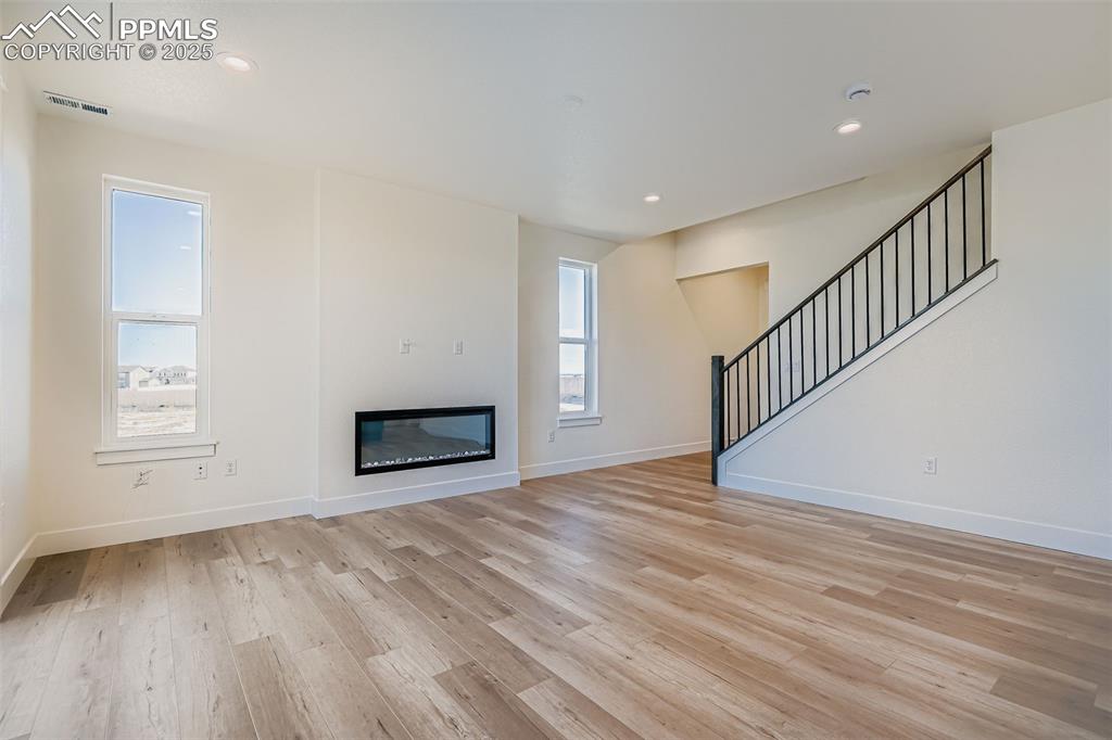 Image 5 of 28: Unfurnished living room featuring a glass covered fireplace, recessed light