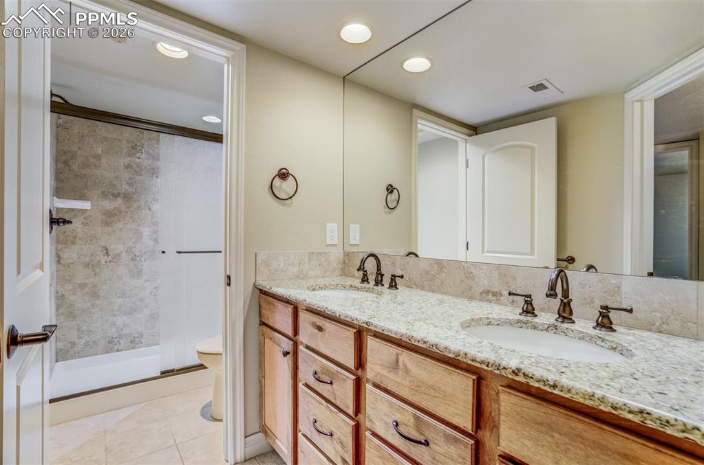 Image 27 of 38: Basement bath offers double vanity and separate tub/toilet area