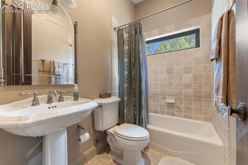 Image 15 of 50: First full bathroom with a pedestal sink and a transom window for light and