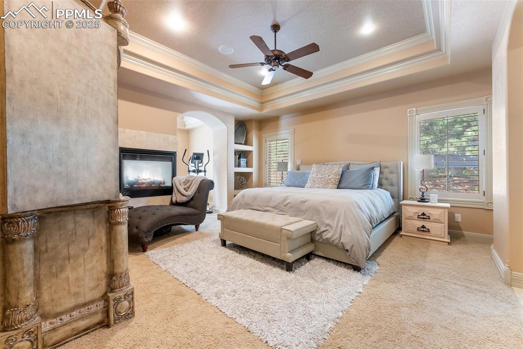 Image 16 of 50: Large primary bedroom with coffered ceiling and built-ins