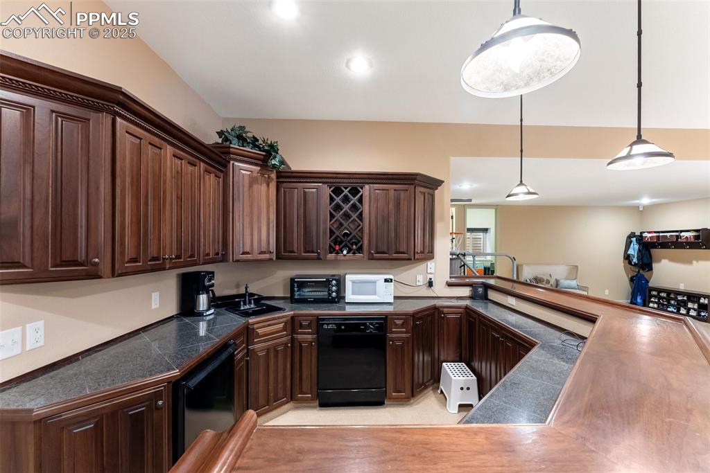 Image 34 of 50: Large wet bar with dishwasher, refrigerator, wine rack and tile countertops