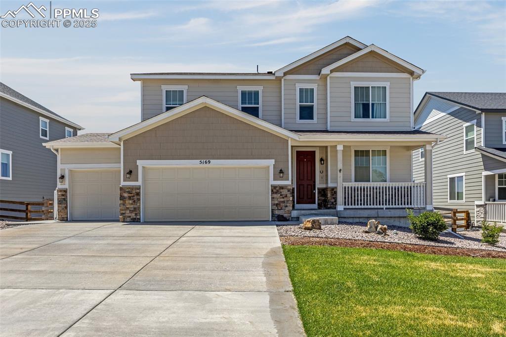 Caption: View of front of property featuring a porch, a garage, driveway, and stone siding