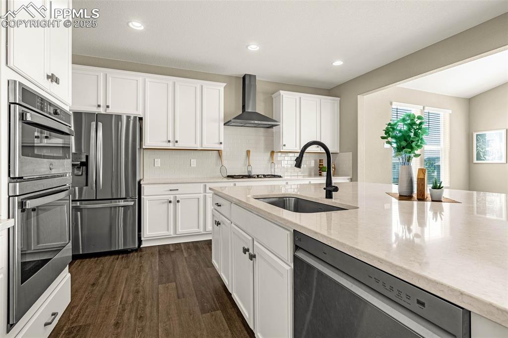 Image 15 of 42: Kitchen with stainless steel appliances, backsplash, white cabinets, and re