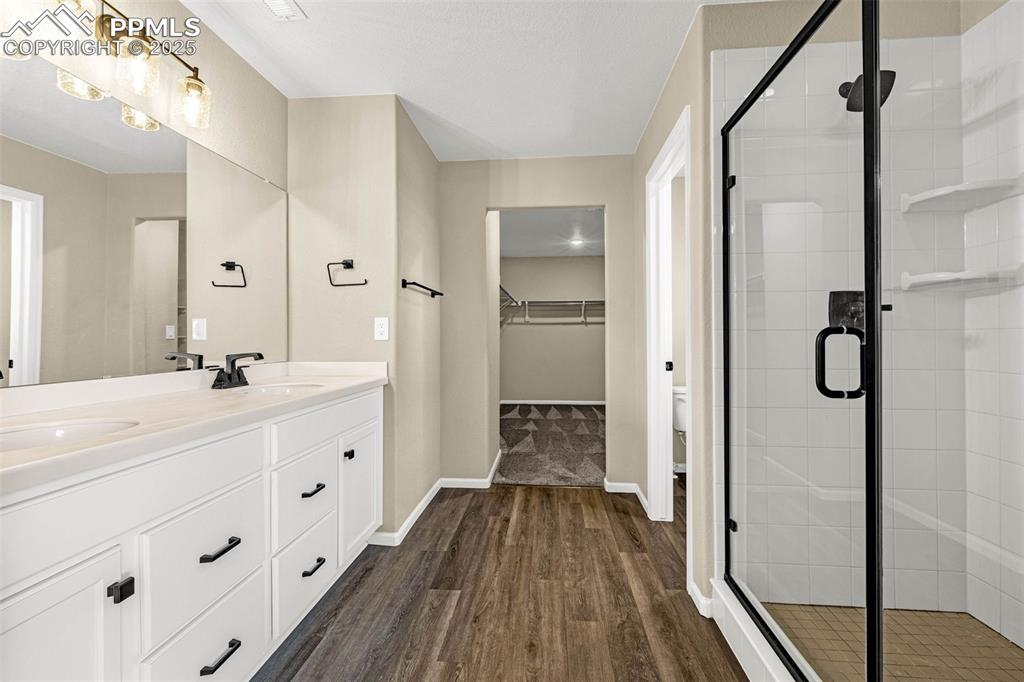 Image 19 of 42: Bathroom with double vanity, a stall shower, dark wood finished floors, and