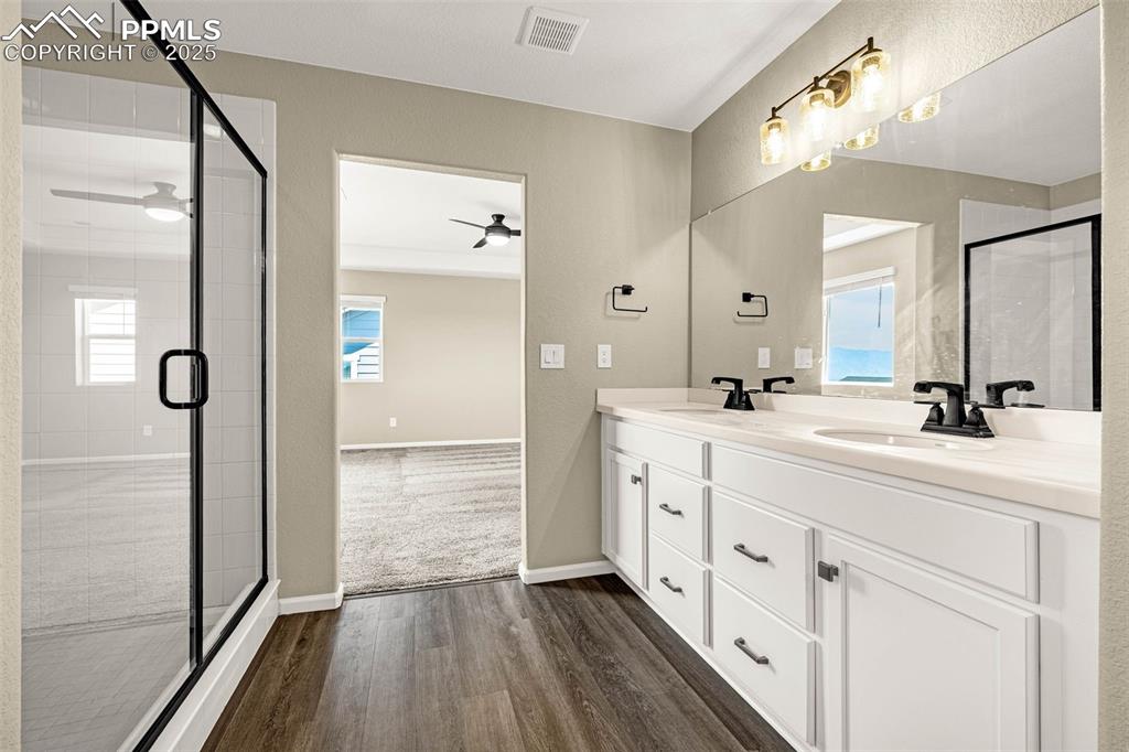 Image 24 of 42: Bathroom with double vanity, dark wood finished floors, and a stall shower