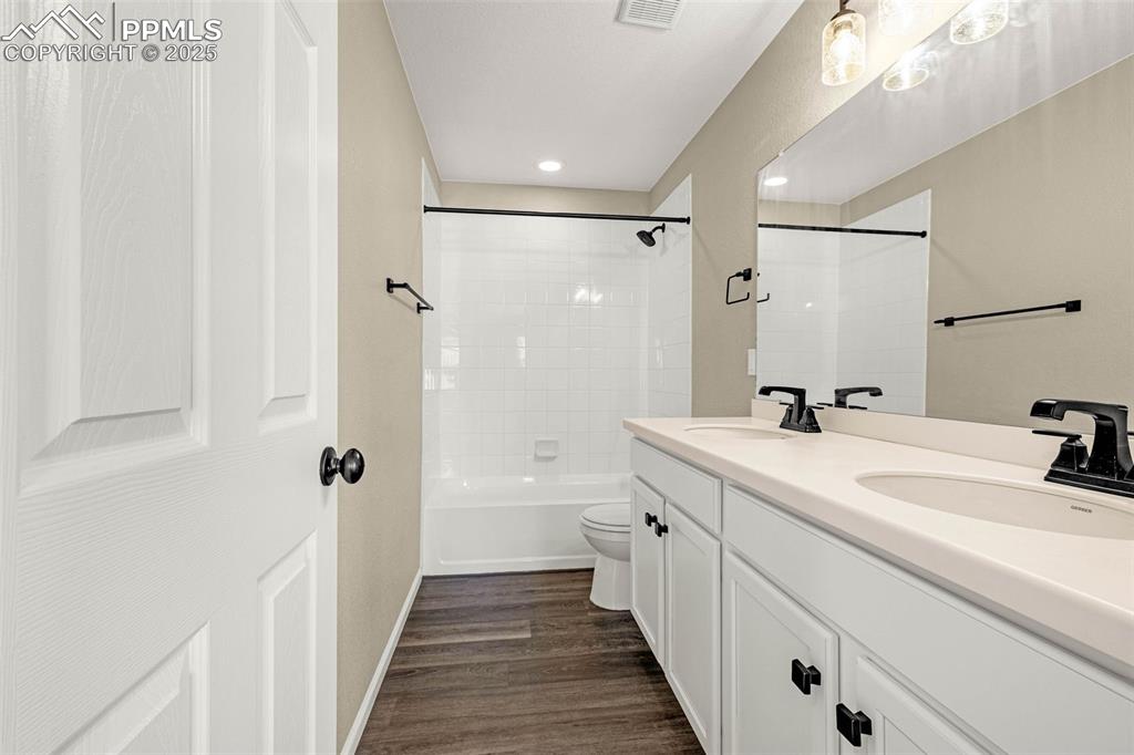 Image 27 of 42: Bathroom featuring double vanity, shower / bath combination, dark wood-type