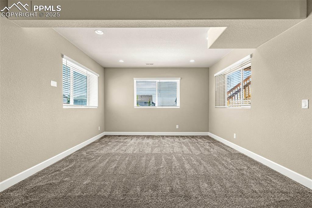 Image 30 of 42: Unfurnished room with a textured wall, carpet floors, and recessed lighting