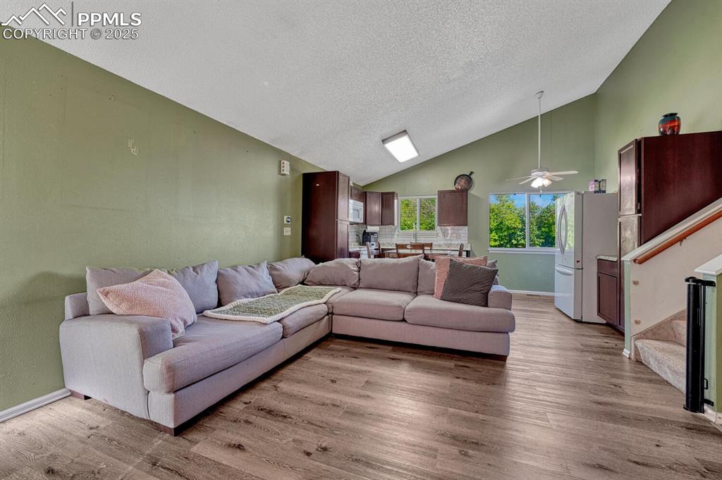 Image 7 of 47: Great room with luxury vinyl plank floor and vaulted ceiling
