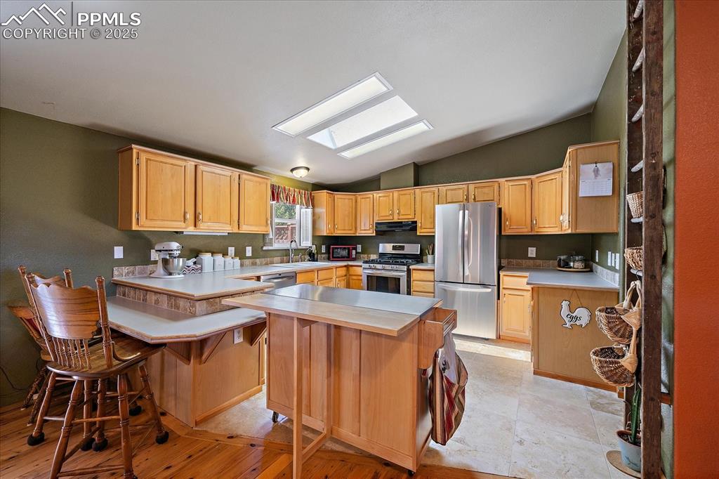 Image 10 of 50: Kitchen featuring vaulted ceiling, light countertops, a skylight, a kitchen