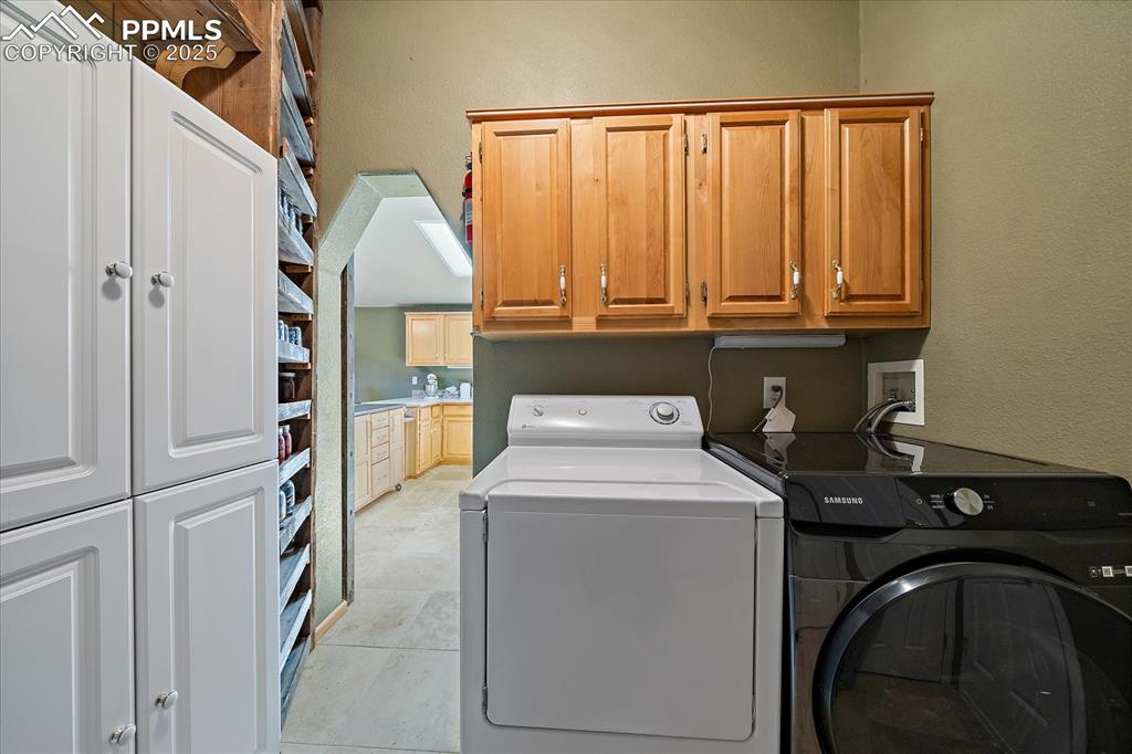 Image 14 of 50: Washroom featuring cabinet space and washing machine and dryer