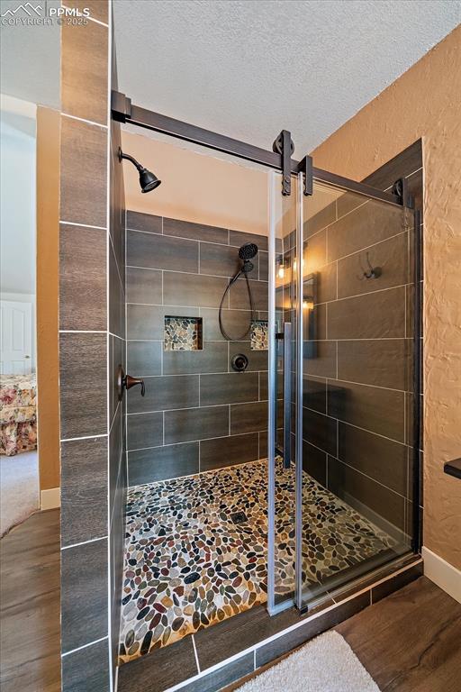 Image 19 of 50: Bathroom featuring a stall shower, dark wood-style flooring, a textured cei
