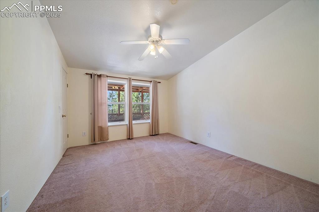Image 23 of 50: Empty room with light colored carpet and a ceiling fan