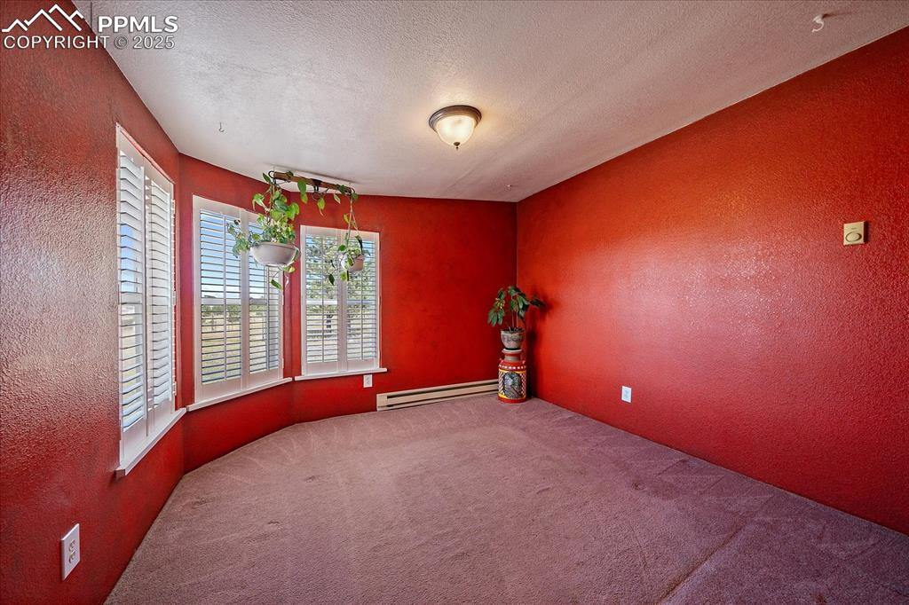 Image 26 of 50: Empty room with a textured wall, a textured ceiling, carpet, and a baseboar
