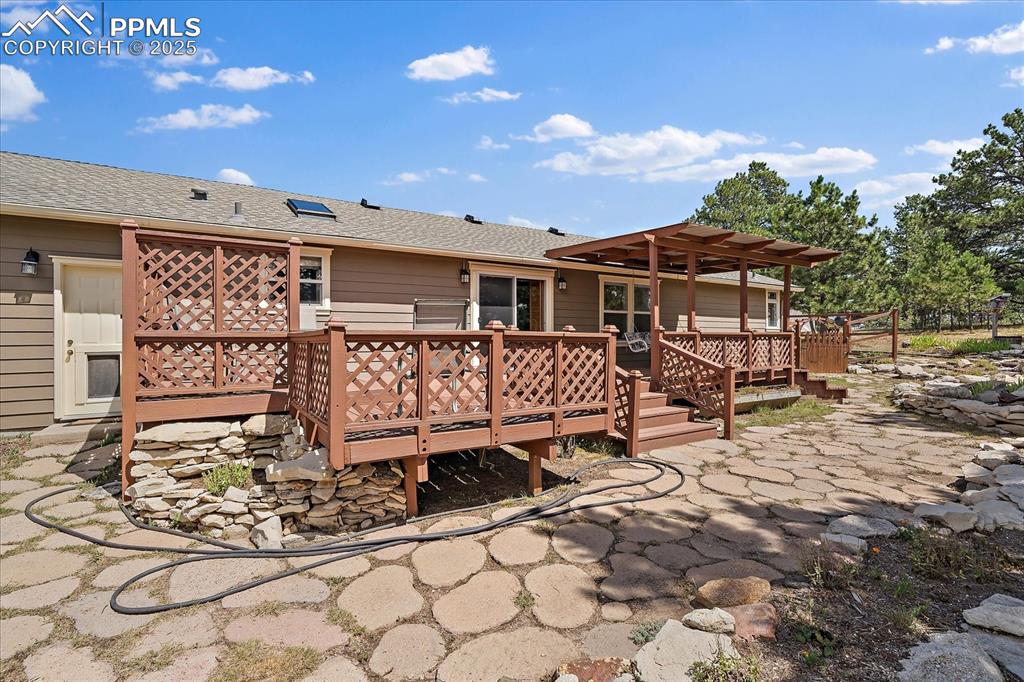 Image 29 of 50: Rear view of property featuring a wooden deck and roof with shingles