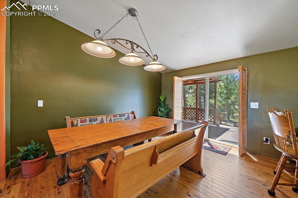 Image 9 of 50: Dining space with a textured wall, light wood finished floors, and lofted c