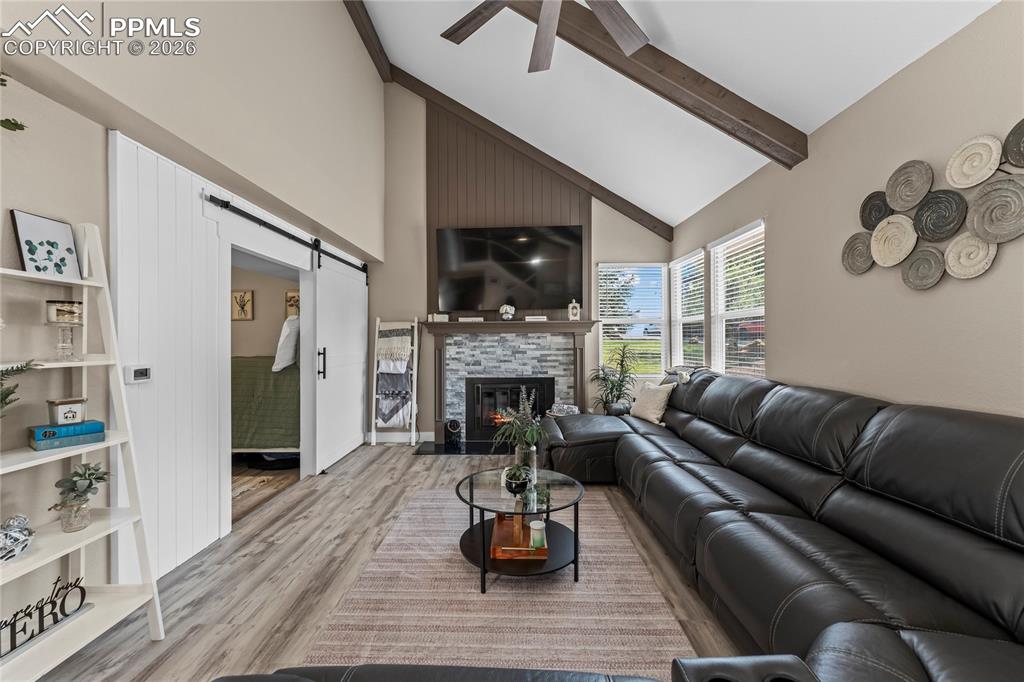 Image 11 of 44: Living area with a barn door, high vaulted ceiling, wood finished floors, a