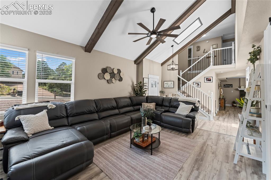 Image 12 of 44: Living area featuring a ceiling fan, beamed ceiling, high vaulted ceiling,