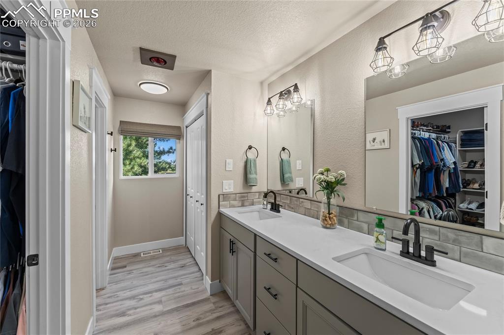 Image 16 of 44: Bathroom with double vanity, a textured ceiling, a walk in closet, wood fin