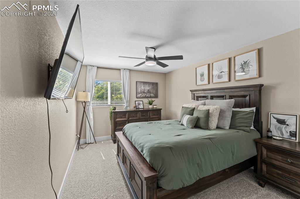 Image 19 of 44: Bedroom featuring a textured ceiling, light carpet, and a ceiling fan