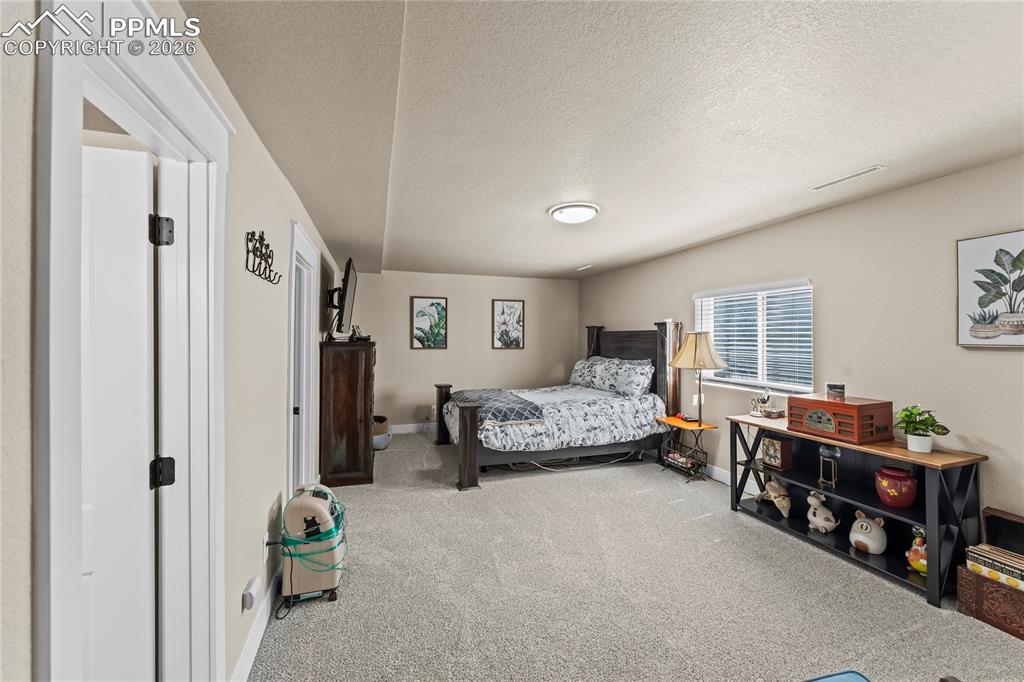 Image 21 of 44: Carpeted bedroom featuring a textured ceiling and baseboards