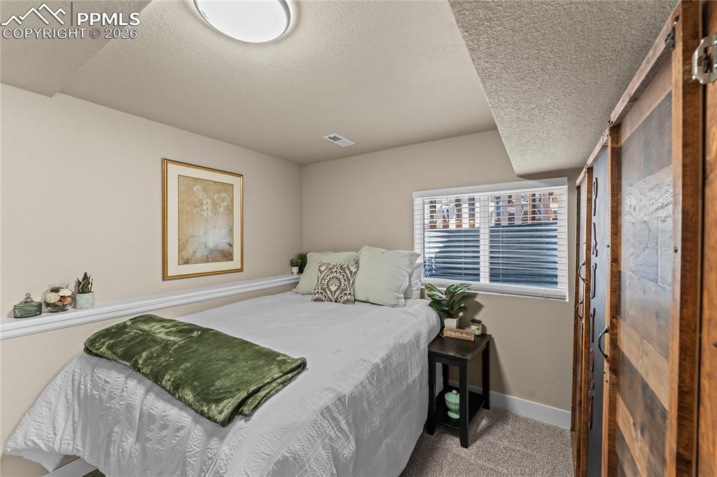 Image 24 of 44: Carpeted bedroom with a textured ceiling and baseboards