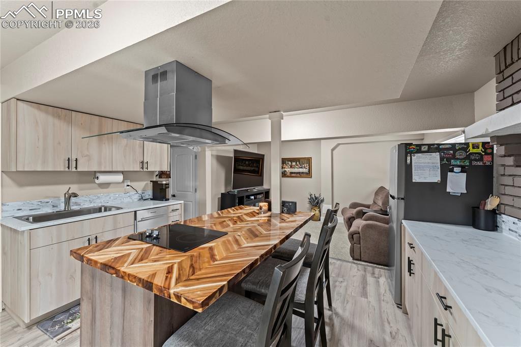 Image 26 of 44: 2nd Kitchen in apartment with island range hood, light wood-style flooring,