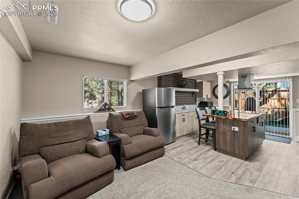 Image 28 of 44: Living area in apartment with light wood-style flooring and a textured ceil