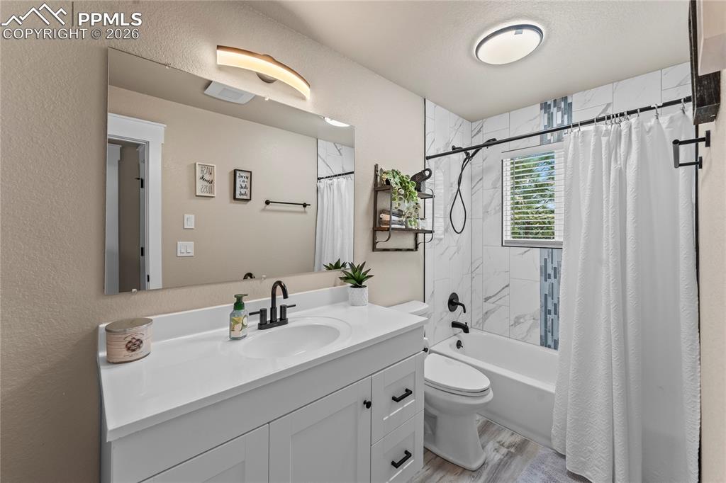 Image 31 of 44: Bathroom featuring vanity, shower / bath combination with curtain, wood fin