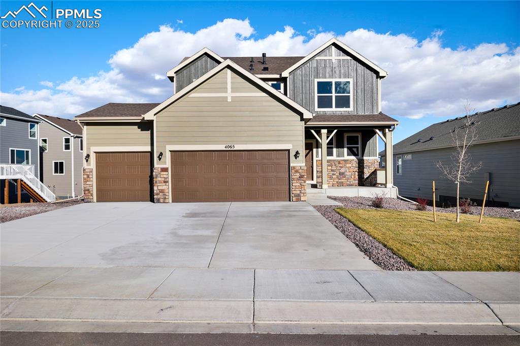 Caption: Craftsman house featuring stone siding, concrete driveway, a front lawn, and a garage